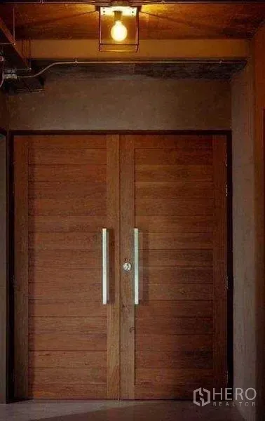 Office Space for rent or sale in Lak Si, Bangkok - Solid double wooden entry doors with metal handles under a warm ceiling light in an industrial hallway.