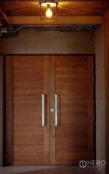 Office Space for rent or sale in Lak Si, Bangkok - Solid double wooden entry doors with metal handles under a warm ceiling light in an industrial hallway.