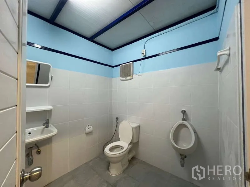 Warehouse for rent in Lat Krabang, Bangkok - Clean tiled restroom with toilet, urinal, sink and mirror inside the warehouse.