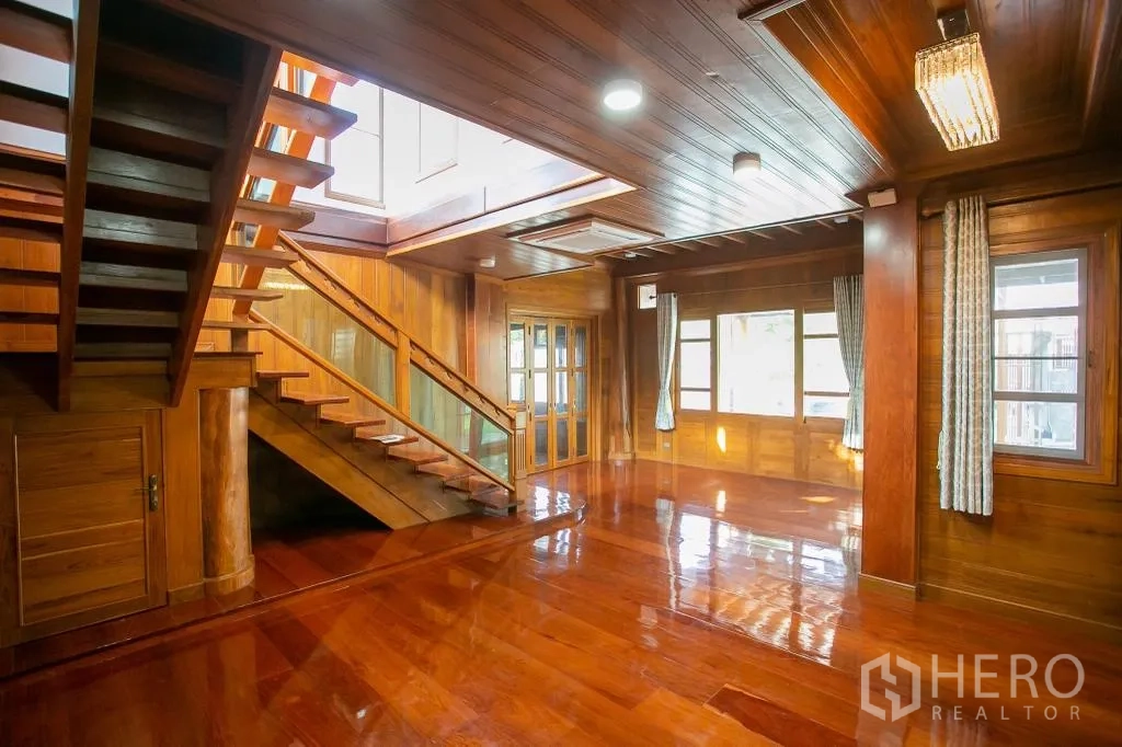 Detached House for rent or sale in Huai Khwang, Bangkok - Large open‑plan living area with glossy wooden floors, windows and stairs.