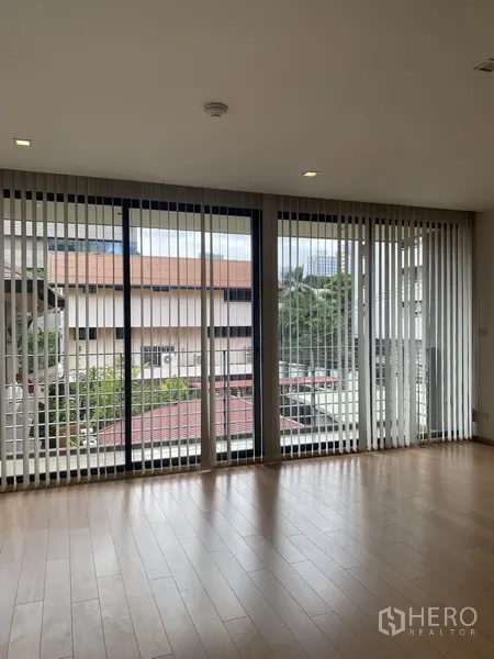 คอนโด ให้เช่าในPathum Wan, Bangkok - ห้องนั่งเล่นคอนโดสว่าง ผนังกระจกเต็มบาน ม่านปรับแสง และพื้นไม้ มองเห็นบรรยากาศปทุมวัน