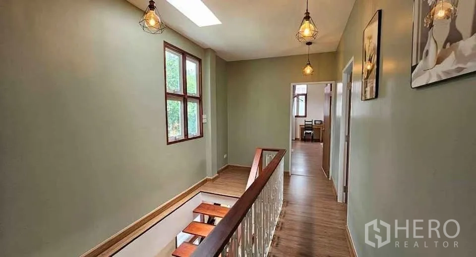 บ้าน ให้เช่าในKhlong Toei, Bangkok - โถงชั้นบนมีสกายไลท์ โคมแขวน ผนังสีเขียว และราวบันไดไม้