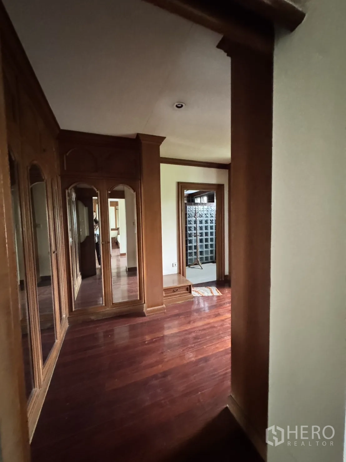 Home Office for rent in Watthana, Bangkok - Hallway with built-in mirrored wardrobes and polished hardwood floors.
