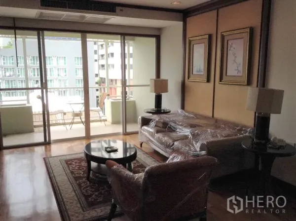 คอนโด ให้เช่าหรือขายในWatthana, Bangkok - ห้องนั่งเล่นพื้นไม้ เปิดสู่ระเบียงพร้อมชุดโต๊ะและวิวเมืองในคอนโดกรุงเทพฯ