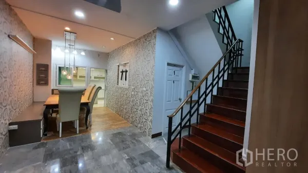 Townhouse for sale in Suan Luang, Bangkok - Dining area beside patterned feature wall and wooden staircase