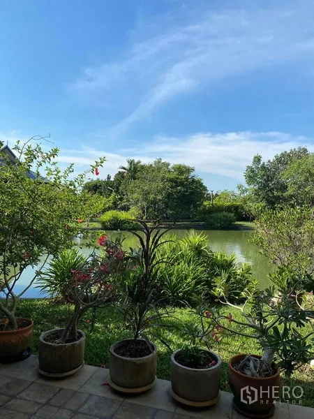 Detached House for sale in Bang Bo, Samut Prakan - Terrace view over a tranquil pond and lush garden with potted plants.