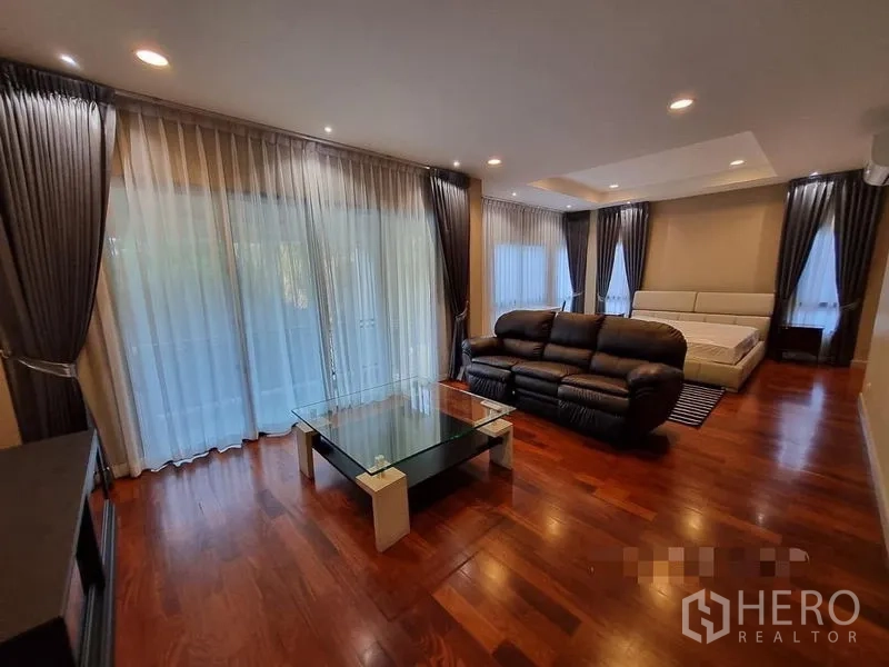 Detached House for rent in Bang Khae, Bangkok - Large suite with seating area, bed and floor-to-ceiling curtains on two sides.