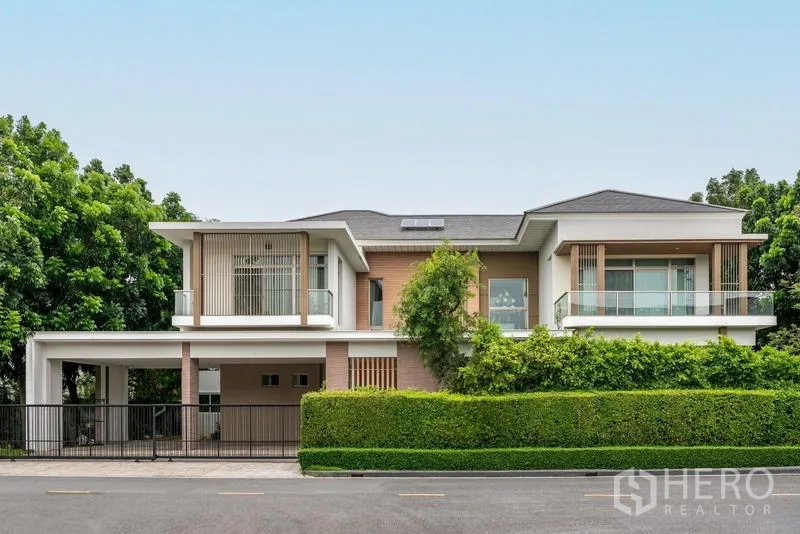 บ้าน ขาย - ด้านหน้าบ้านเดี่ยวสไตล์โมเดิร์นสองชั้น พร้อมรั้วพุ่มและระเบียง