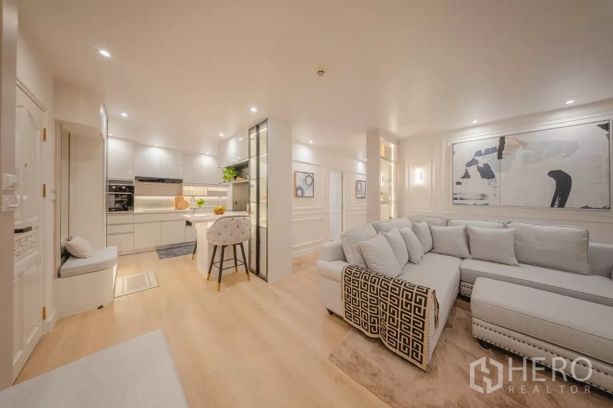 Condominium for rent in Yan Nawa, Bangkok - Open-plan layout with sleek white kitchen, island seating and lounge area.