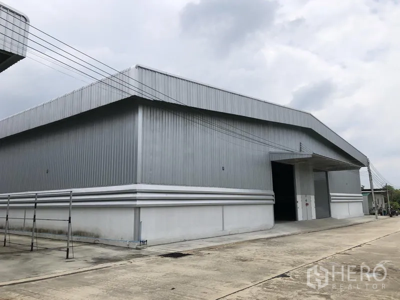 Warehouse for rent in Lat Lum Kaeo, Pathum Thani - Modern steel-clad warehouse exterior with wide driveway and loading bay.