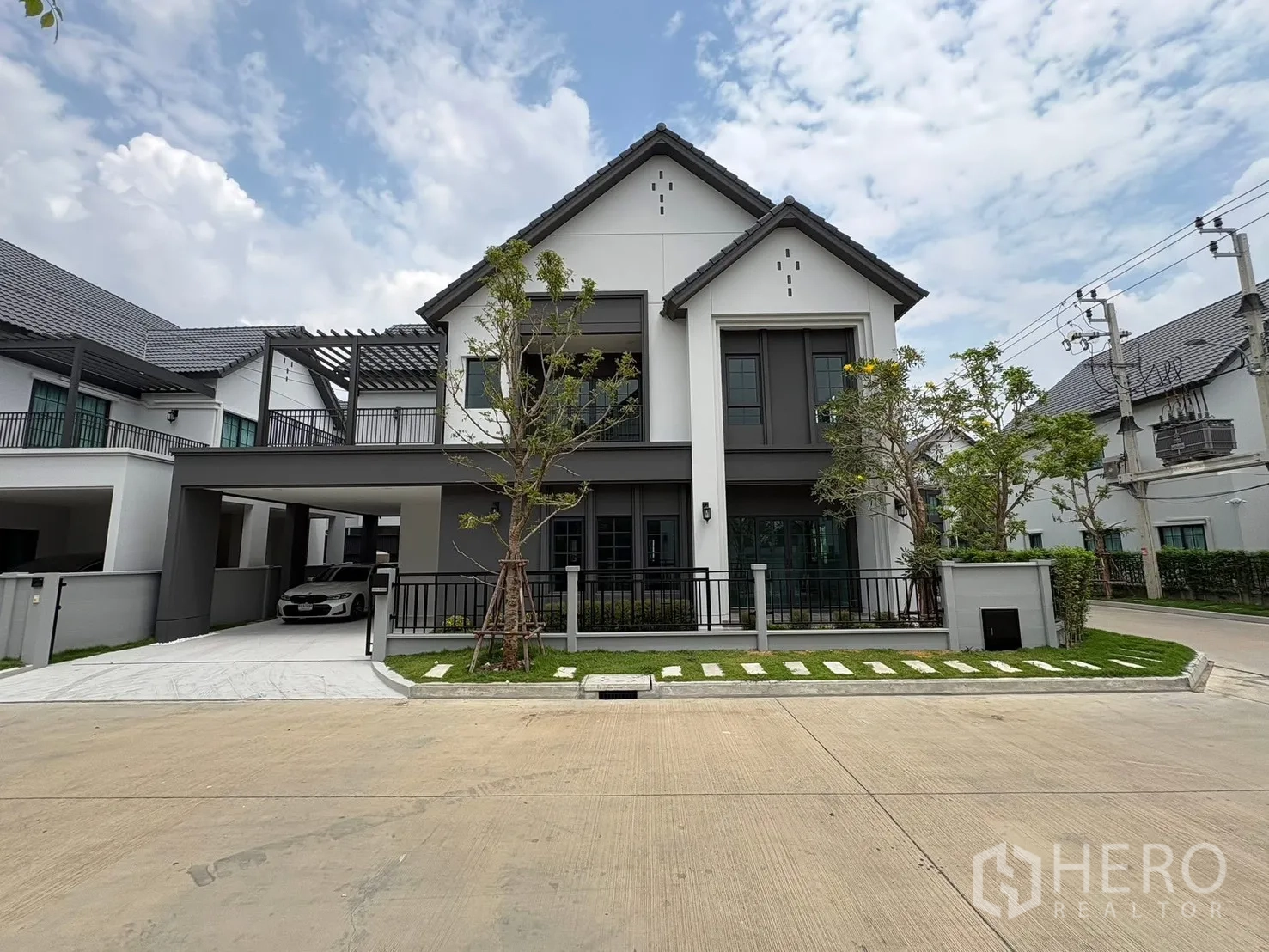 Detached House for rent in Bang Phli, Samut Prakan - Modern two-storey detached house exterior with covered carport, front lawn and trees.