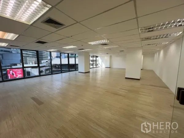 办公空间 出租 - 宽敞办公楼层，转角落地窗、结构柱与网格天花灯，采光充足。