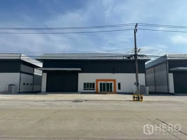 โรงงาน ให้เช่าในBang Sao Thong, Samut Prakan - ด้านหน้าโรงงานสมัยใหม่ ประตูม้วนขนาดใหญ่ ทางเข้าออฟฟิศกระจก และลานคอนกว้าง