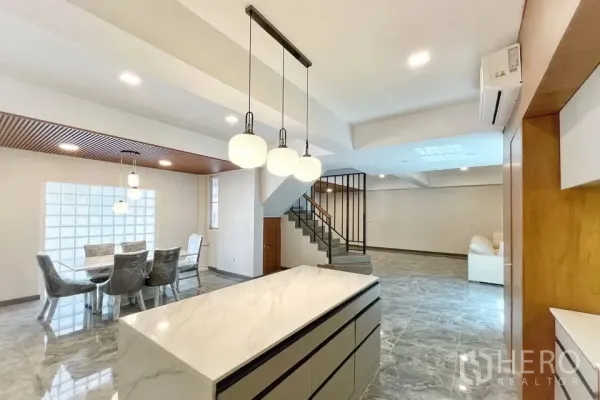 Home Office for rent in Watthana, Bangkok - Open-plan living area with marble floors, island kitchen, pendant lights and a staircase.