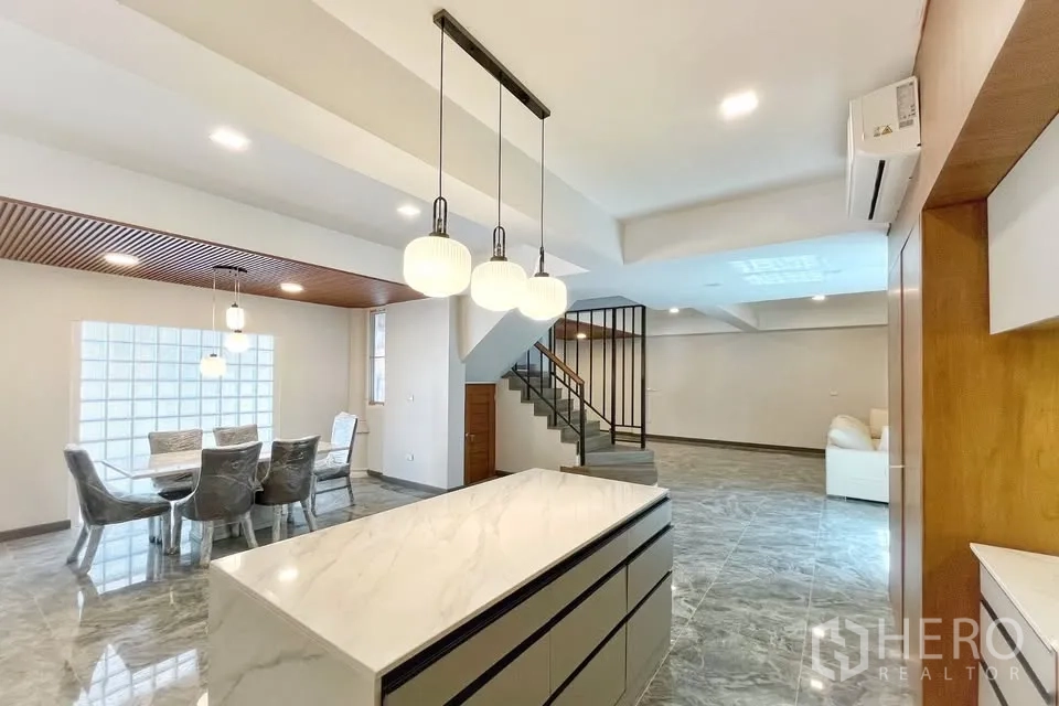 Home Office for rent in Watthana, Bangkok - Open-plan living area with marble floors, island kitchen, pendant lights and a staircase.