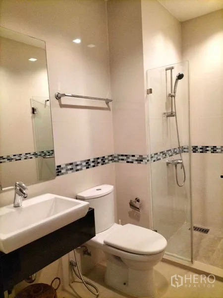 公寓 出租在Ratchathewi, Bangkok - 明亮浴室，玻璃淋浴间、洗手台和坐便器。