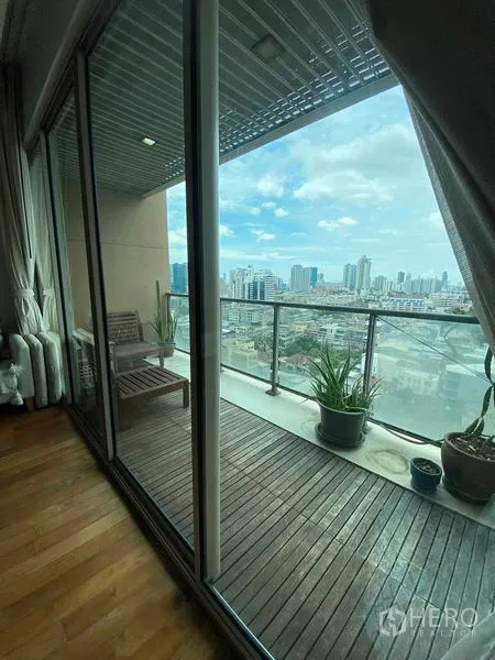 Condominium for rent in Yan Nawa, Bangkok - Covered balcony with wooden decking, potted plants, and a wide panoramic skyline of Bangkok.