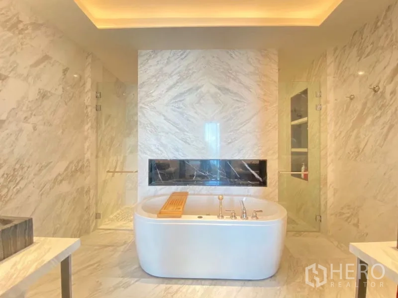 Condominium for rent in Khlong San, Bangkok - Luxurious marble bathroom featuring a freestanding soaking tub flanked by glass-enclosed showers.