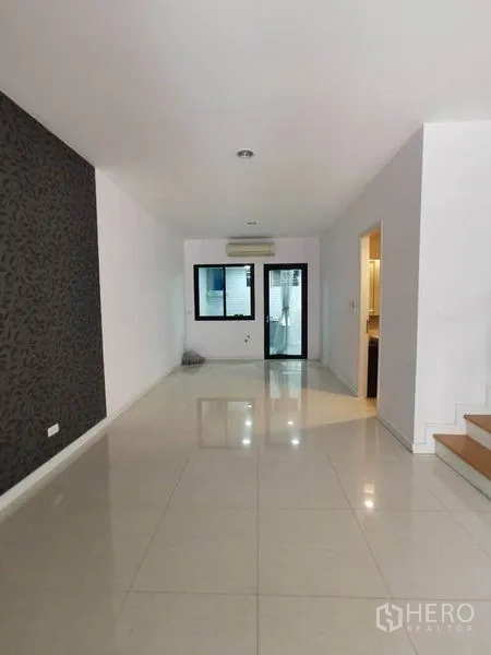 Townhouse for rent in Yan Nawa, Bangkok - Bright open-plan living area with glossy tile floors, feature wall, and stairs in a Bangkok townhouse.