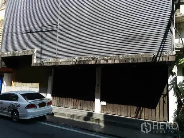 สำนักงานที่บ้าน ให้เช่าในKhlong Toei, Bangkok - ด้านหน้าอาคารสไตล์ช้อปเฮาส์ พร้อมประตูเหล็กม้วนและที่จอดริมทาง.