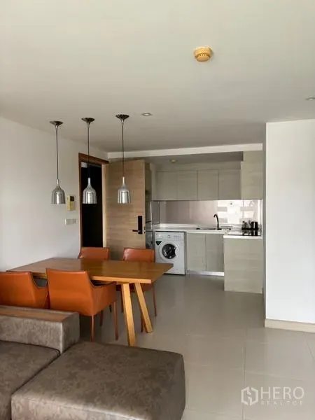 คอนโด ให้เช่าในWatthana, Bangkok - พื้นที่นั่งเล่นและรับประทานอาหารมองไปยังครัวขนาดกะทัดรัด พร้อมโคมไฟแขวนและเครื่องซักผ้า