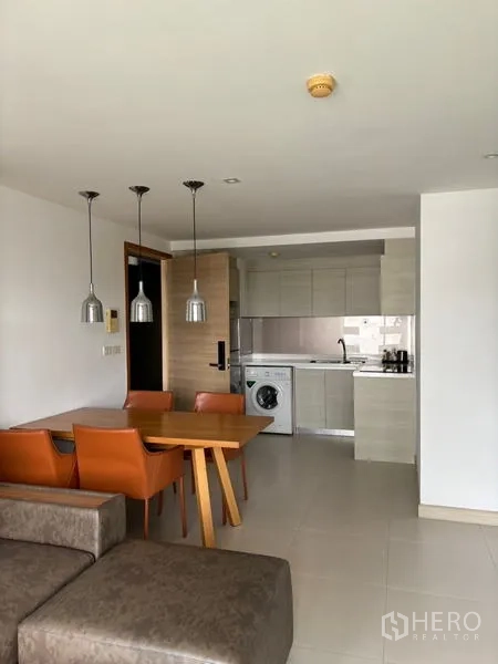 คอนโด ให้เช่าในWatthana, Bangkok - พื้นที่นั่งเล่นและรับประทานอาหารมองไปยังครัวขนาดกะทัดรัด พร้อมโคมไฟแขวนและเครื่องซักผ้า