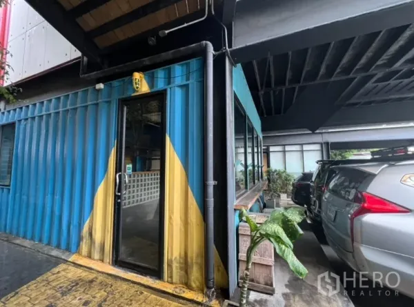 พื้นที่ขายปลีก ให้เช่า - ด้านนอกยูนิตค้าปลีกตู้คอนเทนเนอร์สีน้ำเงิน ประตูกระจก ข้างที่จอดรถ ใกล้เอกมัย