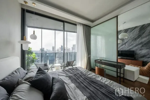 公寓 出租在Khlong Toei, Bangkok - 卧室带书桌并可滑门直达阳台，俯瞰Khlong Toei城市景观。