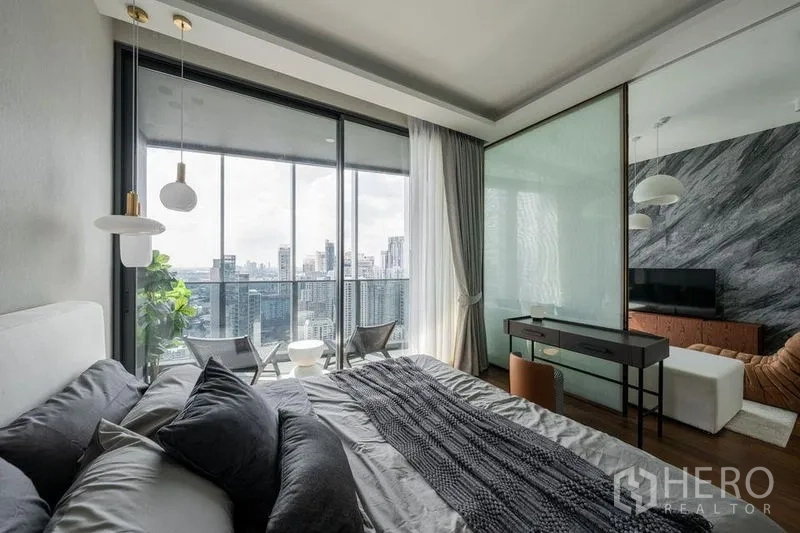 公寓 出租在Khlong Toei, Bangkok - 卧室带书桌并可滑门直达阳台，俯瞰Khlong Toei城市景观。