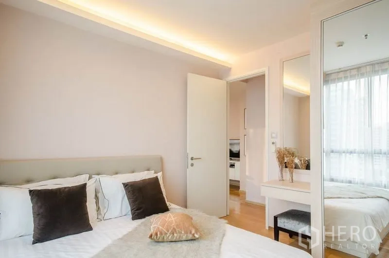 คอนโด ให้เช่าหรือขายในWatthana, Bangkok - ห้องนอนหลักอบอุ่น มีไฟซอฟต์ไลต์ โต๊ะเครื่องแป้ง และตู้เสื้อผ้าบานกระจก