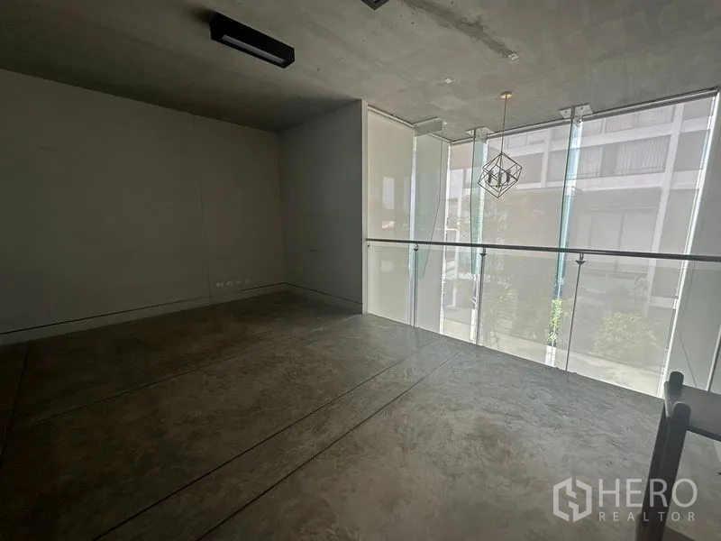 Home Office for rent in Phra Khanong, Bangkok - Mezzanine workspace overlooking tall frosted windows with a glass balustrade.