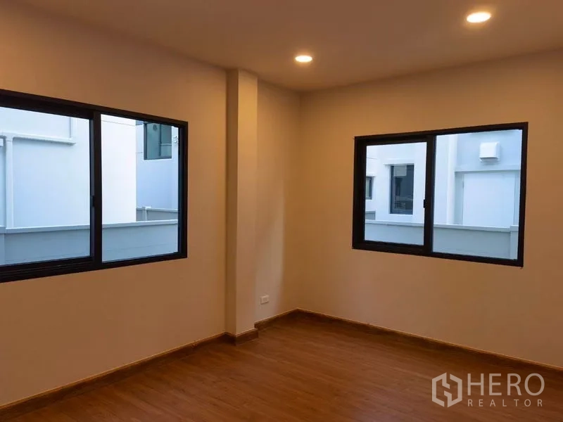 Detached House for rent in Bang Phli, Samut Prakan - Bedroom with wood floors and dual windows bringing in natural light.