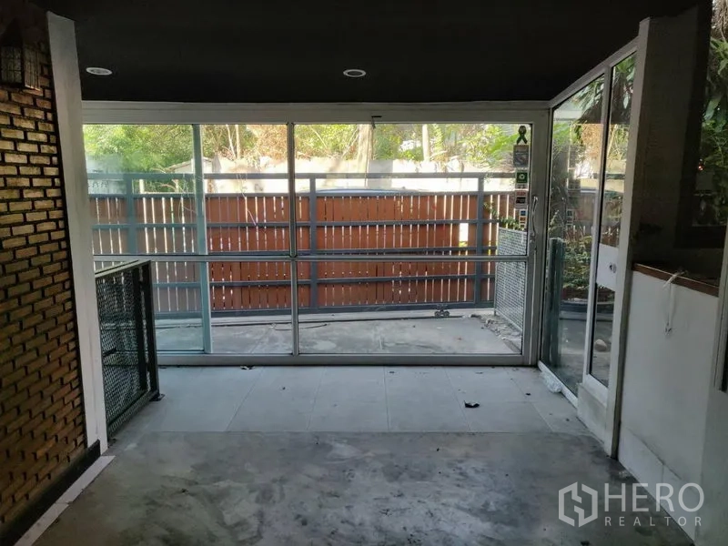 Home Office for rent in Watthana, Bangkok - Covered front area with sliding glass doors and view of the wooden fence.