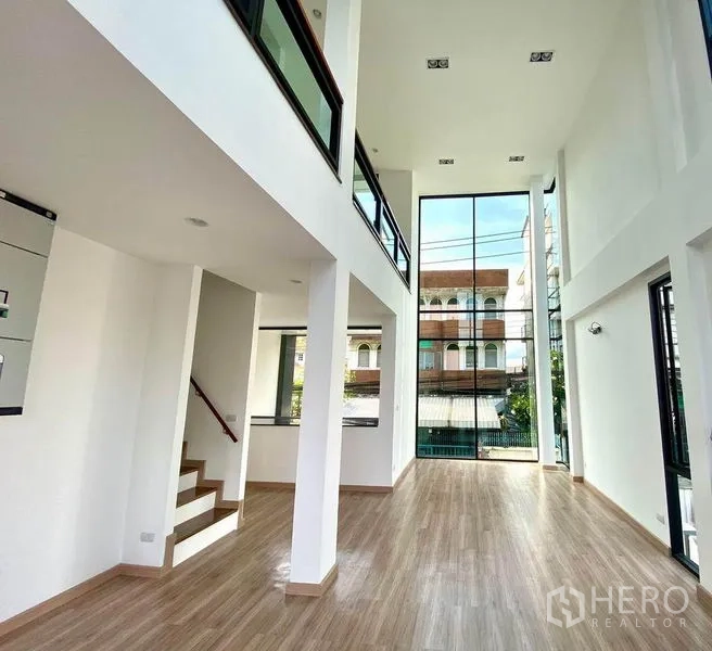 Home Office for sale in Wang Thonglang, Bangkok - Open-plan double-height hall with a glass wall, columns and stair to mezzanine.