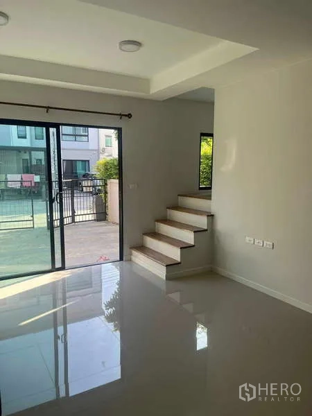 ทาวน์เฮาส์ ให้เช่าในSuan Luang, Bangkok - ห้องนั่งเล่นมีบันได ประตูกระจกบานเลื่อนออกสู่เฉลียงหน้าบ้าน พื้นกระเบื้องมันวาว