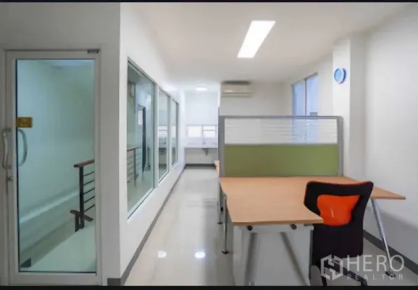 Home Office for rent or sale in Lat Krabang, Bangkok - Corridor with glass walls and desk area receiving natural light and air conditioning.