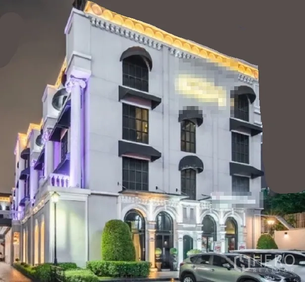พื้นที่ขายปลีก ให้เช่าในHuai Khwang, Bangkok - อาคารพาณิชย์สไตล์นีโอคลาสสิกยามค่ำ แสงไฟโดดเด่น หน้าต่างโค้ง และที่จอดรถ ในย่านห้วยขวาง กรุงเทพฯ