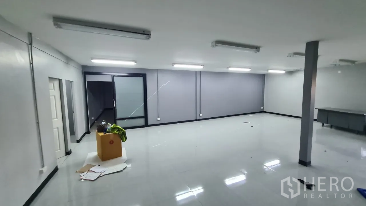 Home Office for rent in Pathum Thani - Large workroom with bright ceiling lights and a glass-enclosed meeting room.