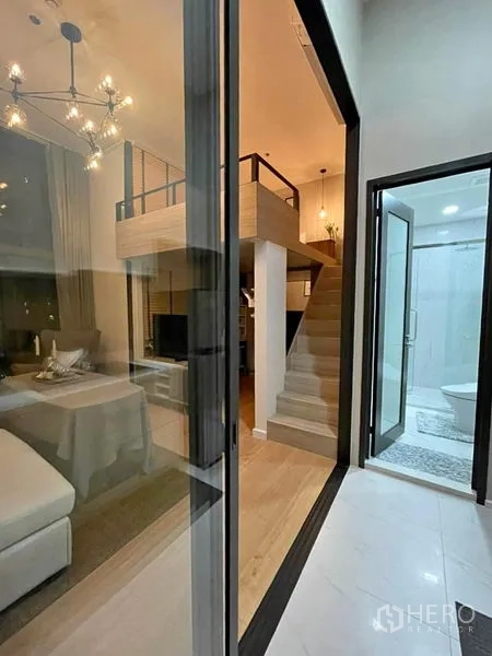 คอนโด ให้เช่าในRatchathewi, Bangkok - มุมมองทางเข้าไปยังห้องนั่งเล่นสไตล์ลอฟท์พร้อมบันไดและห้องน้ำกระจกใกล้กัน