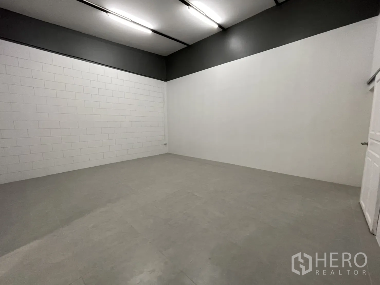 คลังสินค้า ให้เช่าในLam Luk Ka, Pathum Thani - ห้องอเนกประสงค์ผนังบล็อกสีขาว คาดสีเทา พื้นกระเบื้องและไฟหลอดยาว.