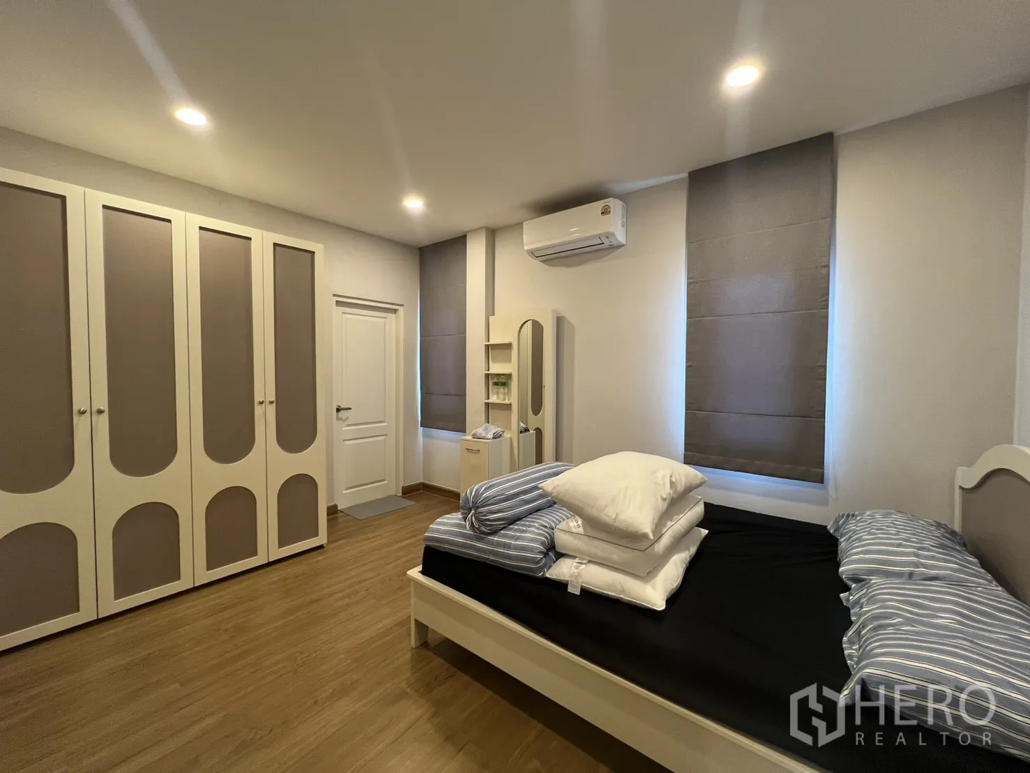 Detached House for rent in Lat Krabang, Bangkok - Bedroom with a wall of wardrobes, bed, recessed lighting, and wood flooring.