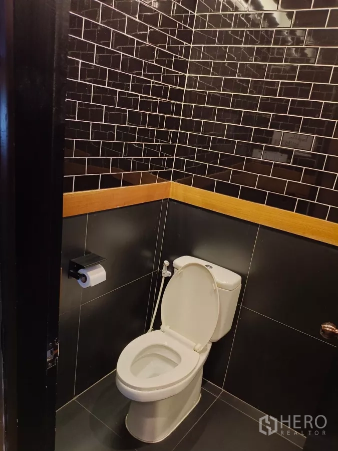 Retail Space for rent - Toilet room with black subway tiles and handheld bidet spray.