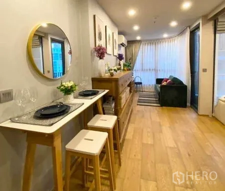 คอนโด ขายในRatchathewi, Bangkok - พื้นที่รับประทานอาหารและนั่งเล่นแบบเปิดโล่ง พื้นไม้ หน้าต่างบานใหญ่ และโซฟาอบอุ่น