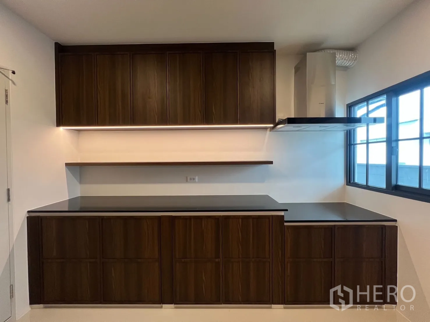 Detached House for rent in Bang Phli, Samut Prakan - Second kitchen angle showing ample counter space, wall cabinets and a cooker hood by the window.