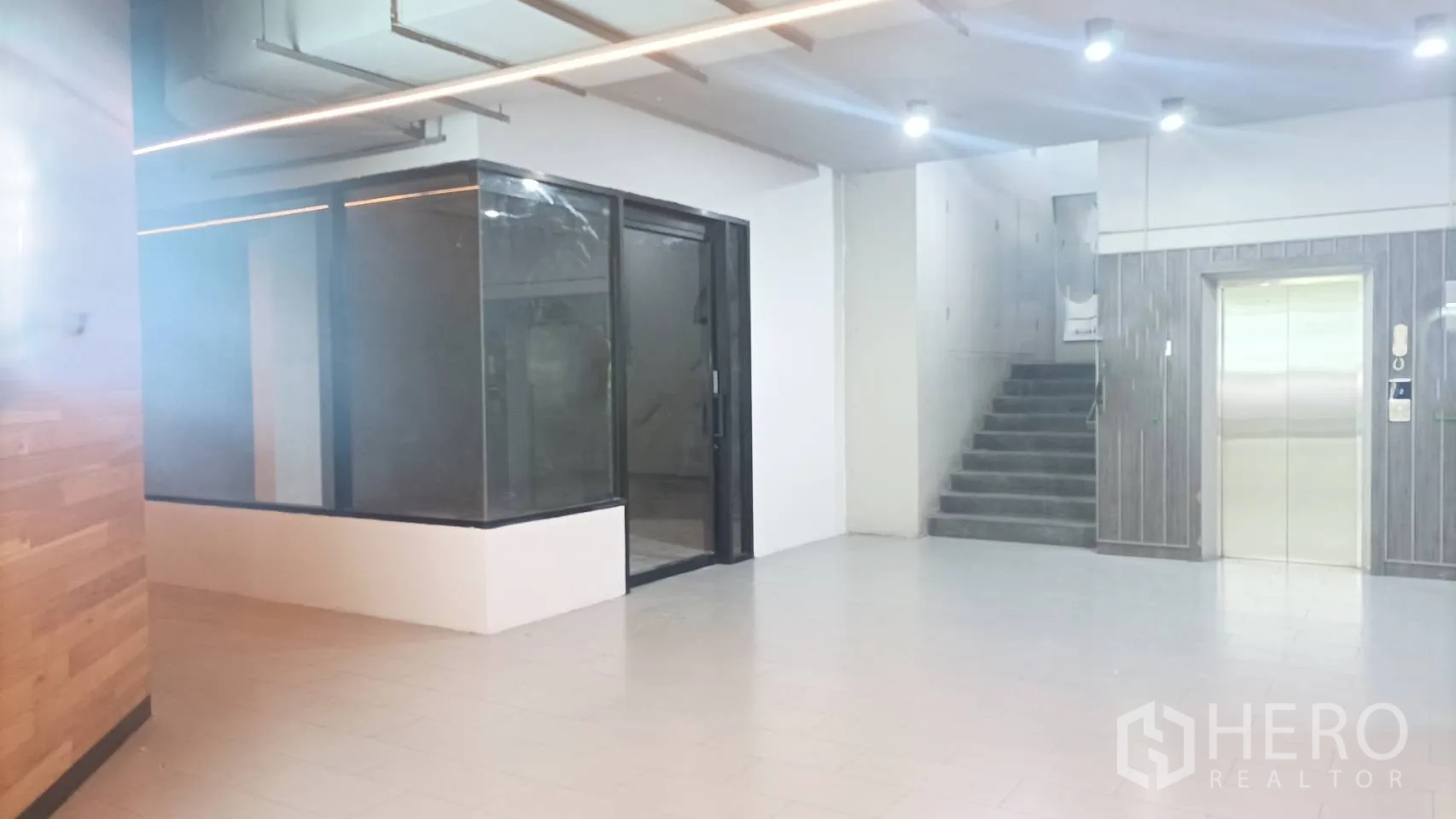 零售空间 出租 - 零售空间邻近客用电梯与楼梯，明亮瓷砖大堂。