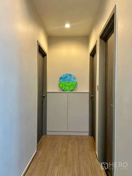 Condominium for sale in Watthana, Bangkok - Well-lit hallway leading to bedrooms and bathrooms with wood flooring.
