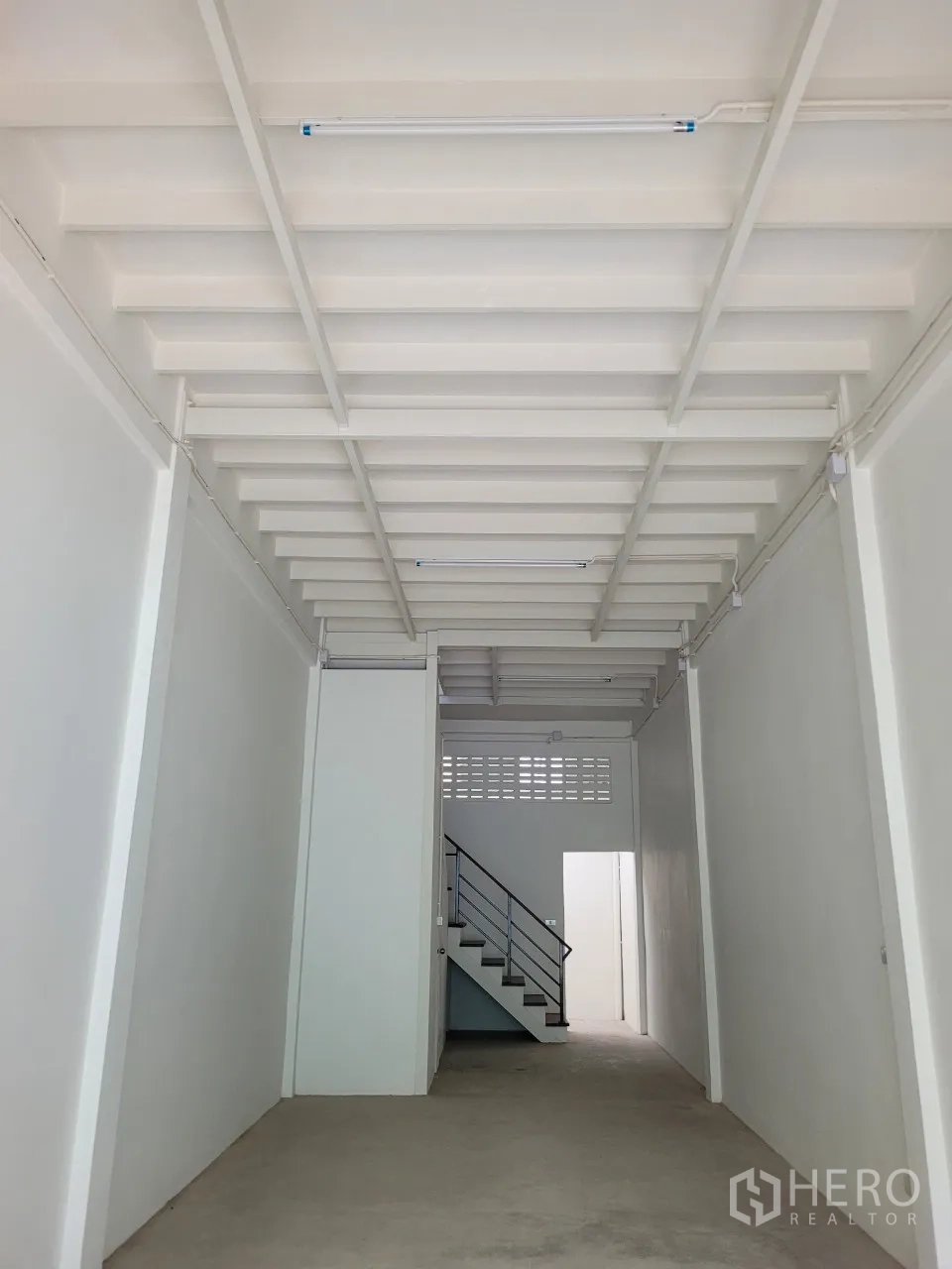 店屋 出租在Khlong Toei, Bangkok - 一层长形空间，墙面新刷，裸露梁架与日光灯。