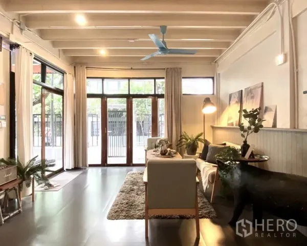 ทาวน์เฮาส์ ให้เช่าในKhlong Toei, Bangkok - ห้องนั่งเล่นสว่างด้วยประตูกระจกสูงจรดเพดาน เพดานคานเปลือยและโซฟาชุด