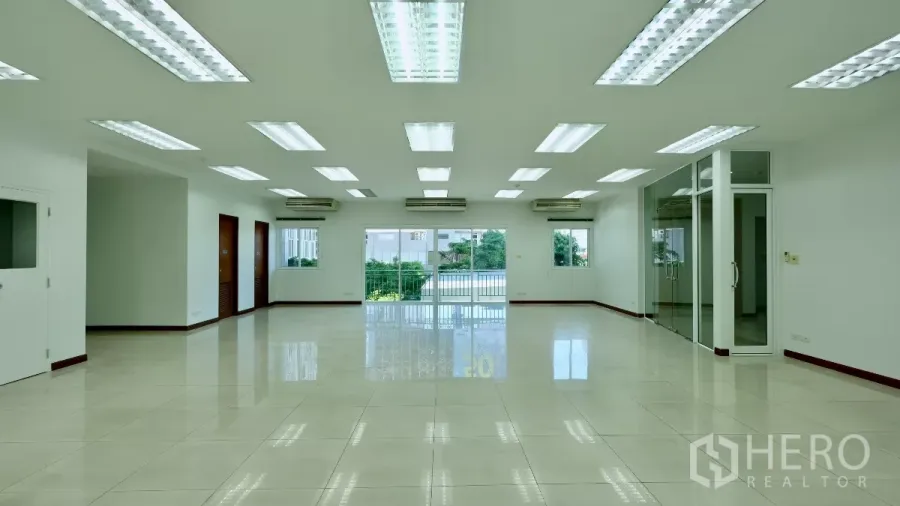 Office Space for rent - Spacious open-plan office with tiled floors, LED ceiling lights, multiple air conditioners, a glass meeting room, and sliding doors to a balcony.