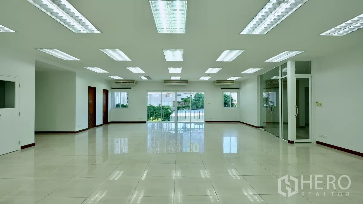 Office Space for rent - Spacious open-plan office with tiled floors, LED ceiling lights, multiple air conditioners, a glass meeting room, and sliding doors to a balcony.